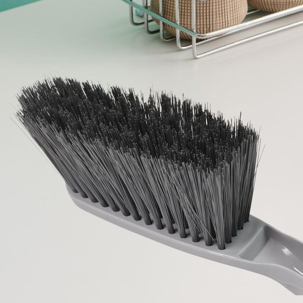 Woman using the long-handle cleaning brush for scrubbing a kitchen sink.
